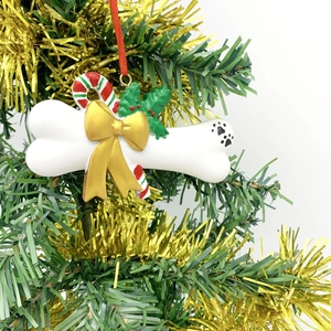 Detail of DIY resin bone ornament with gold bow and paw print on a Christmas tree