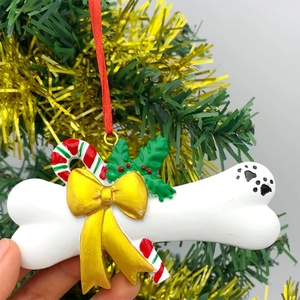 Detail of dog bone resin ornament with gold bow and holly for Christmas tree decor
