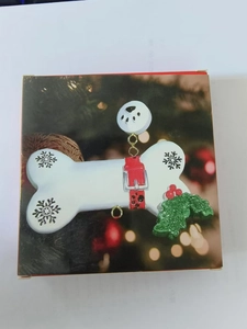 Detail view of bone-shaped resin Christmas ornament with paw print and holly leaf decoration