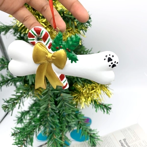 Detailed resin Christmas dog bone ornament with golden bow and festive holly leaves