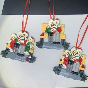 Detail of DIY resin snowman family ornaments on yellow bench with red hanging ribbons