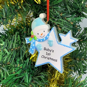 Detail of Snowman and Star resin ornament on Christmas tree with Baby's 1st Christmas text
