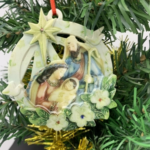 Close-up of a Nativity scene Christmas ornament with star detail on a green festive tree