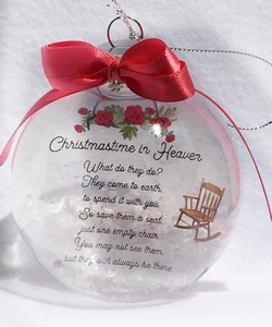 Macro detail of Christmas memorial ornament with red bow, white snow, and rocking chair motif