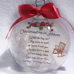 Christmas memorial ball ornament with red rose and wooden chair on snowy white background