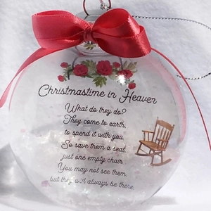 Memorial Christmas ball with red bow, white feathers, and wooden chair illustration