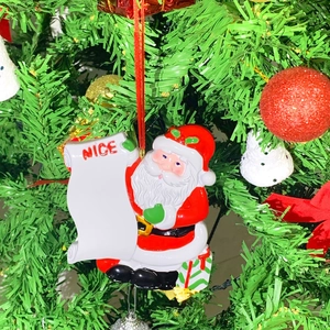 Personalized resin Santa Claus ornament holding a white scroll on a Christmas tree