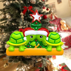 Close-up of two green resin turtles with Christmas hats and a star tree ornament