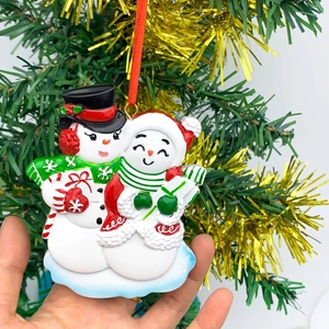 Detailed view of hand-painted resin snowman couple ornament with festive red hanging ribbon