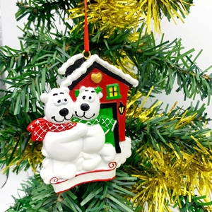 Christmas polar bear house ornament with red ribbons on a festive evergreen tree