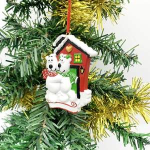 Detail of resin polar bear couple ornament hanging on Christmas tree with red house