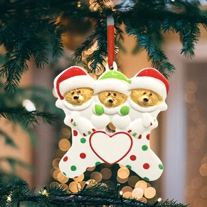 Three Christmas bears with red hats hugging a large heart resin ornament on a festive tree