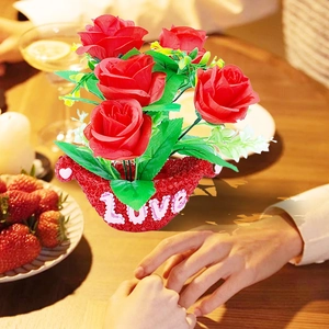 Detail of red artificial rose flower arrangement with Love engraved red textured pot