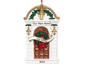 Detailed resin Christmas house ornament featuring a white door frame and festive green wreath