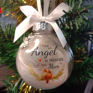 Memorial Christmas ball with white feathers and ribbon on a festive holiday tree