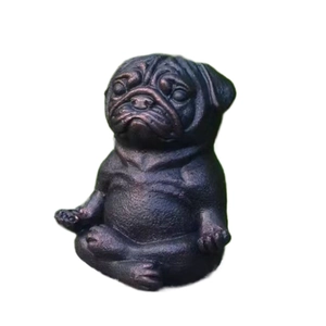 Macro detail of a meditating pug statue with rustic metallic finish in a garden