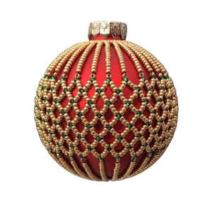 Close-up of red Christmas ornament with gold and green beaded mesh and snowflake cap