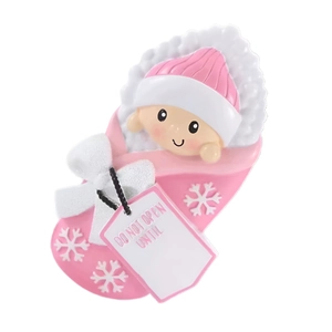Pink resin baby Christmas ornament in snowflake swaddle with a festive gift tag