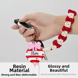 Detail of red heart resin keychain with Mom lettering and pink ribbon on hand