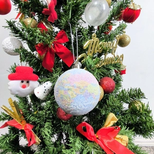 Christmas globe ornament with world map pattern and glitter hanging on a festive tree
