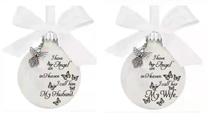 Close-up of white memorial ornaments with silver angel charms and ribbon bows