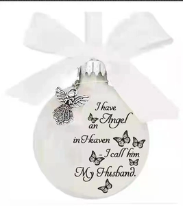 Close-up of commemorative feather ball with white ribbon bow and angel charm