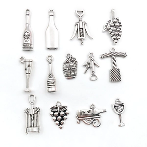 Détail macro de 13 breloques en argent vintage sur le thème du vin, bouteilles et tonneaux