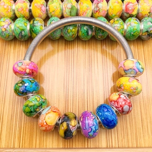 Detailopname van kleurrijke beschilderde kralen op een zilveren spiraalvormige armband