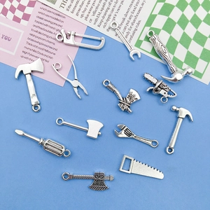 Detailed view of silver miniature alloy tool pendants featuring wrenches, hammers and saws