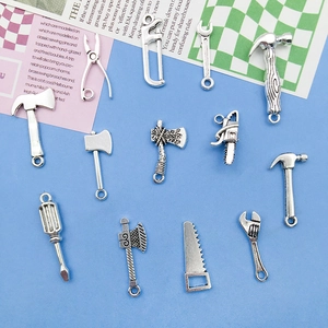 Detailed macro view of vintage silver alloy tool charms including hammer and wrench shapes
