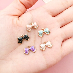 Makroaufnahme von 5 bunten Emaille-Bogenanhängern für DIY-Schmuck in einer Handfläche