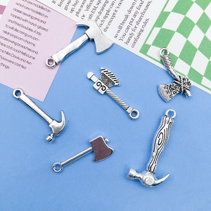 Detailed macro view of antique silver alloy tool pendants including axes and hammers