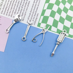 Close-up of four antique silver alloy tool pendants including wrench and pliers charms