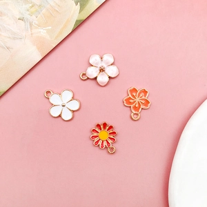 Detail von vier bunten Emaille-Blumenanhängern für DIY-Schmuck mit goldfarbenen Metallösen