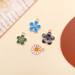 Detail von vier bunten DIY-Blumenanhängern mit Emaille-Blüten und vergoldeten Legierungsringen