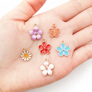 Set aus sechs bunten Emaille-Blumenanhängern in der Hand für die DIY-Schmuckherstellung