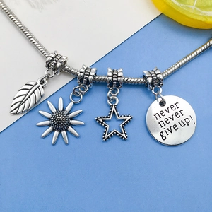 Detail of silver charm bracelet with leaf, sunflower, star and engraved metal pendants