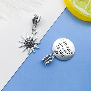 Detail of silver alloy sunflower charm and 'never never give up' round pendant for DIY jewelry