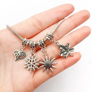 Detailed shot of retro silver snake chain bracelet with heart and snowflake charms