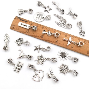 Macro detail of various vintage silver alloy charms showing measurements with a ruler