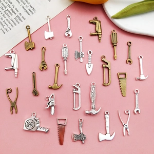 Flachbild von antiken Silber- und Bronze-Miniaturwerkzeug-Anhängern auf rosa Grund