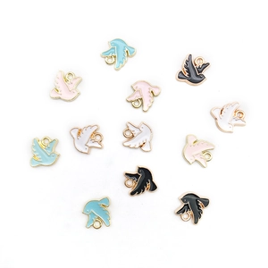 Détail de breloques oiseaux en émail coloré avec bords dorés pour la création de bijoux