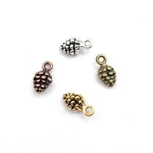 Détail macro de quatre pendentifs pomme de pin en métal doré, argenté, bronze et cuivre