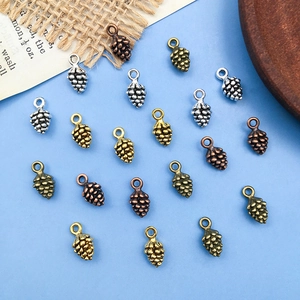 Vue détaillée de pendentifs pommes de pin DIY en métal vintage sur fond bleu rustique