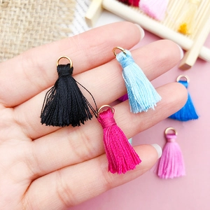Hand holding colorful silk tassels with golden metal rings for DIY jewelry and crafts