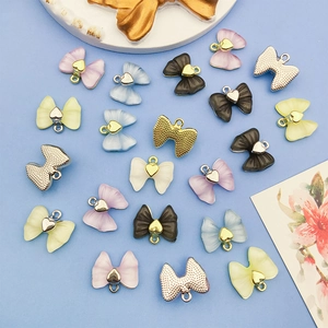 Détails macro de pendentifs nœuds en acrylique avec breloques cœur et dos en maille métal