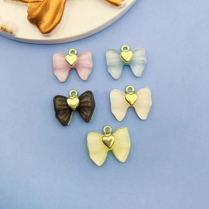 Détail de pendentifs nœuds en acrylique colorés avec cœurs dorés pour bijoux DIY