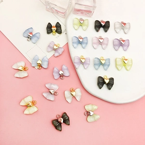 Vue macro de pendentifs nœuds en acrylique colorés avec breloques cœur sur support