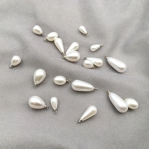 Detailed view of white teardrop pearl charms with silver metal loops for DIY jewelry making