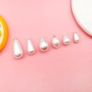 Detail view of six white teardrop pearl pendants in various sizes with silver metal loops